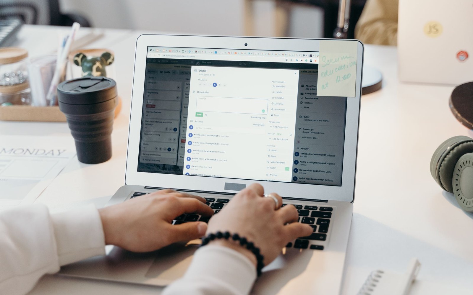Hands typing on a laptop showing a project management app with task cards