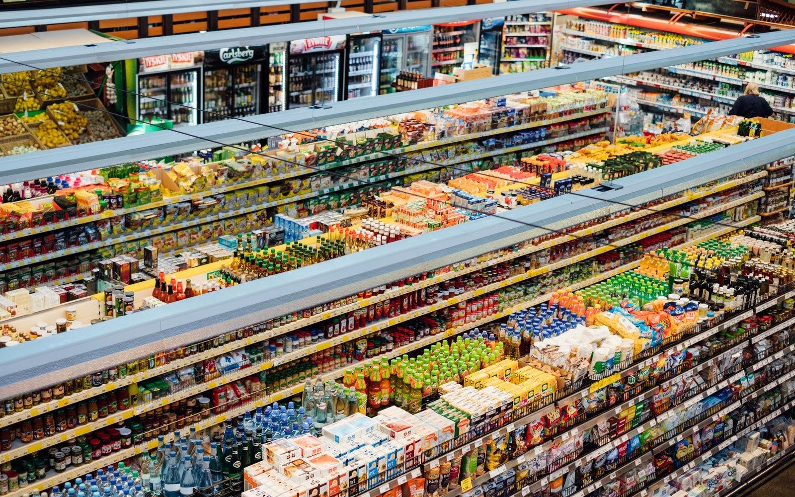 Rows of packaged drinks and snacks fill a supermarket's refrigerated display shelves
