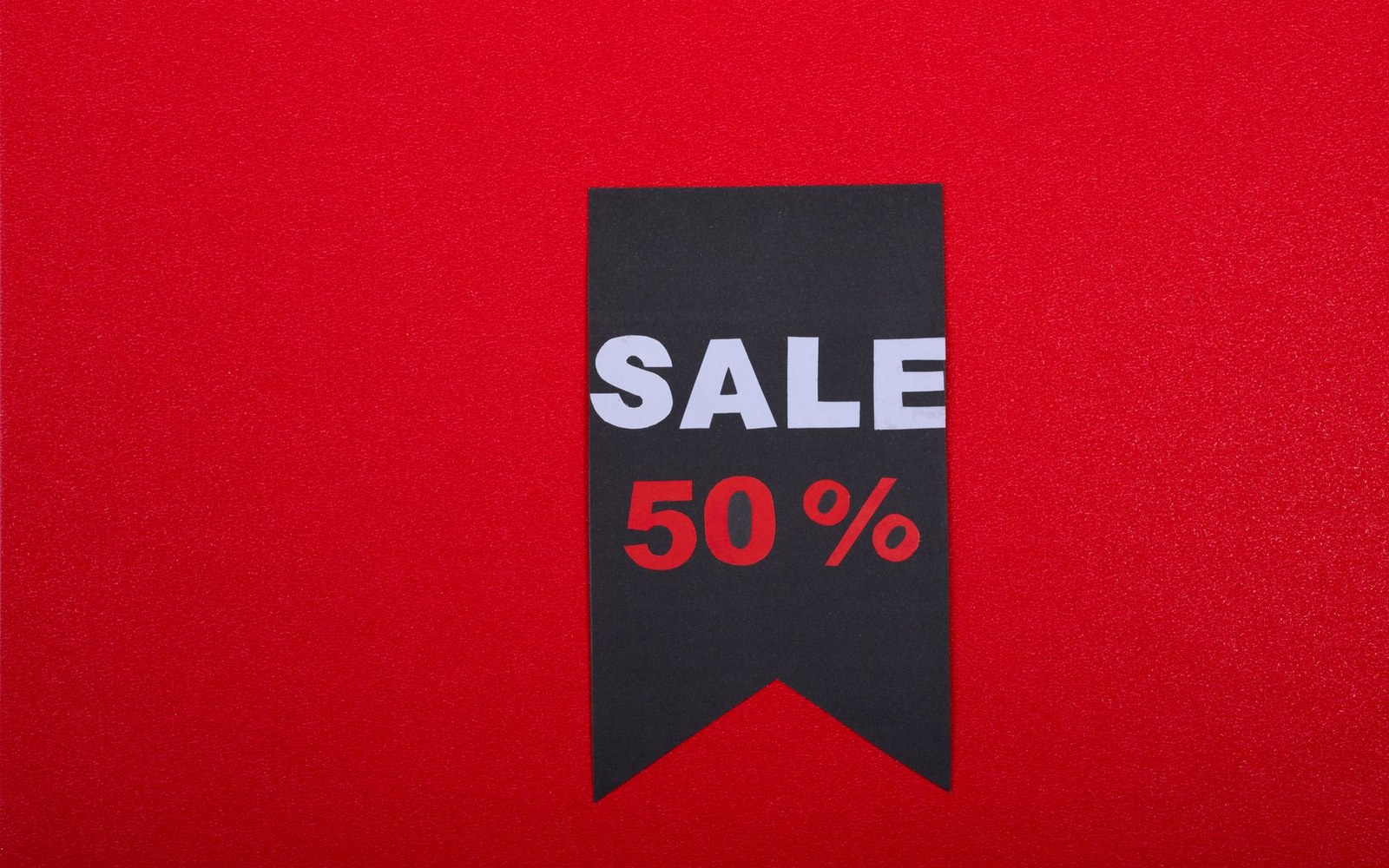 Black bookmark-shaped tag reading "sale 50%" against a red background