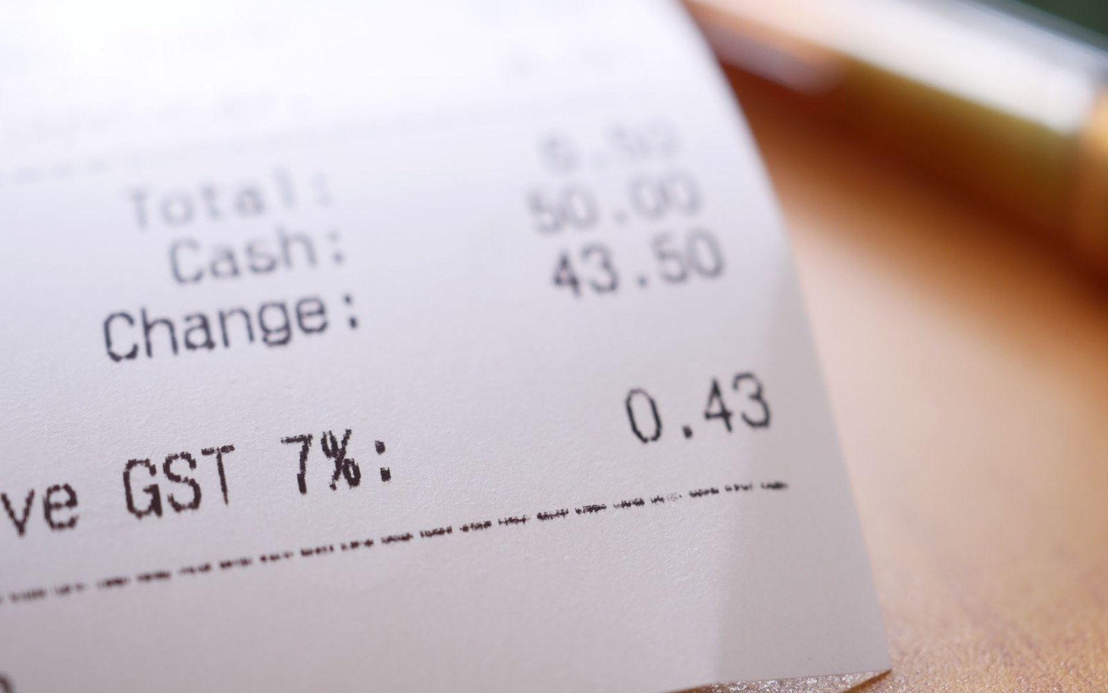 Close-up of a printed receipt showing total, cash, change and 7% GST amounts