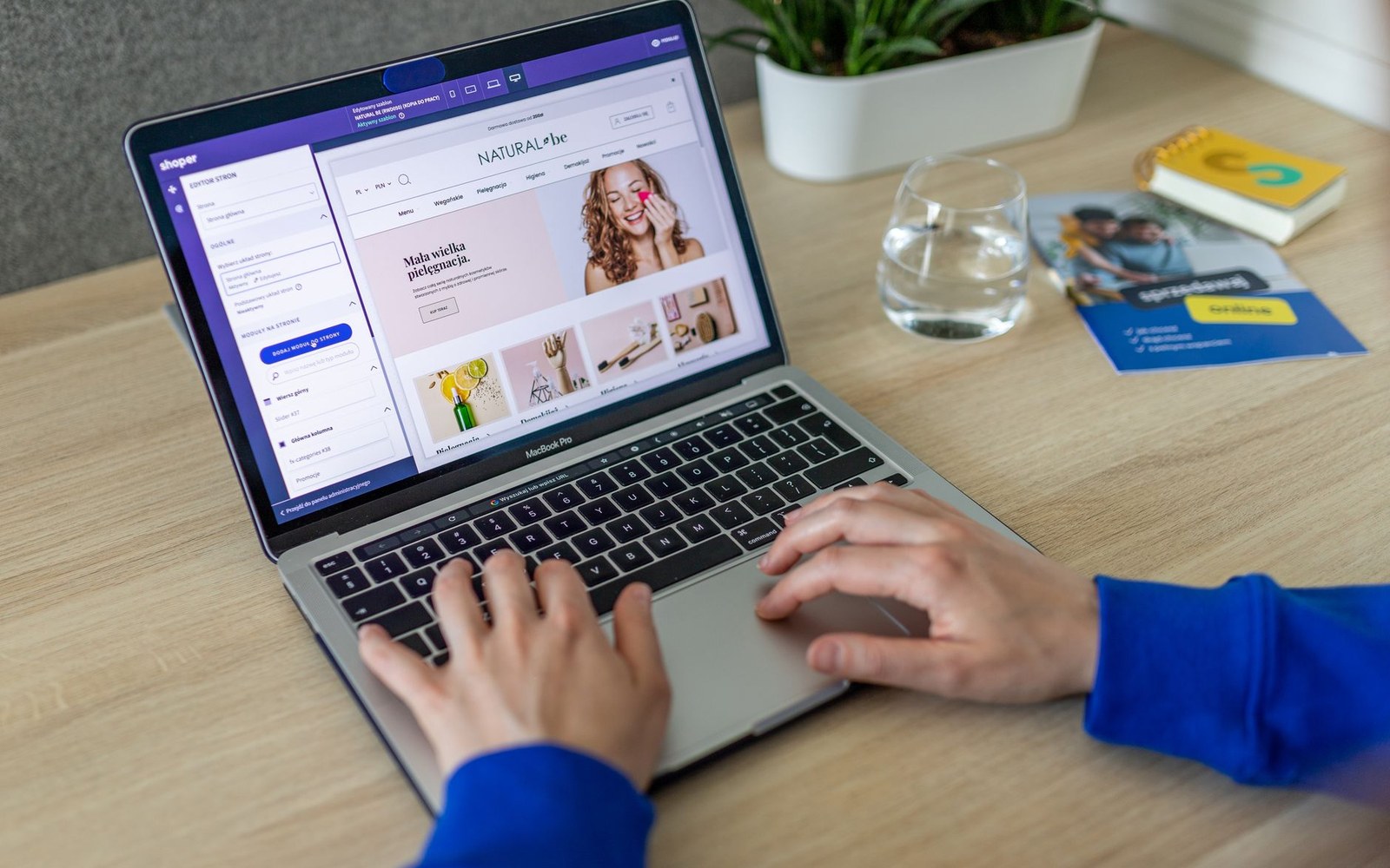 Hands typing on a laptop displaying a beauty brand's online store homepage