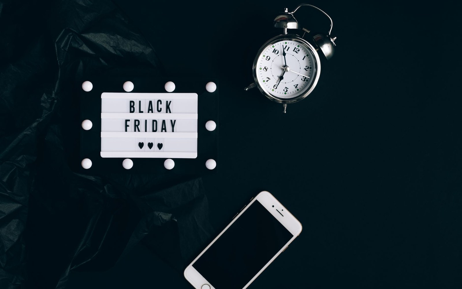 A lightbox sign reading "Black Friday" beside an alarm clock and smartphone