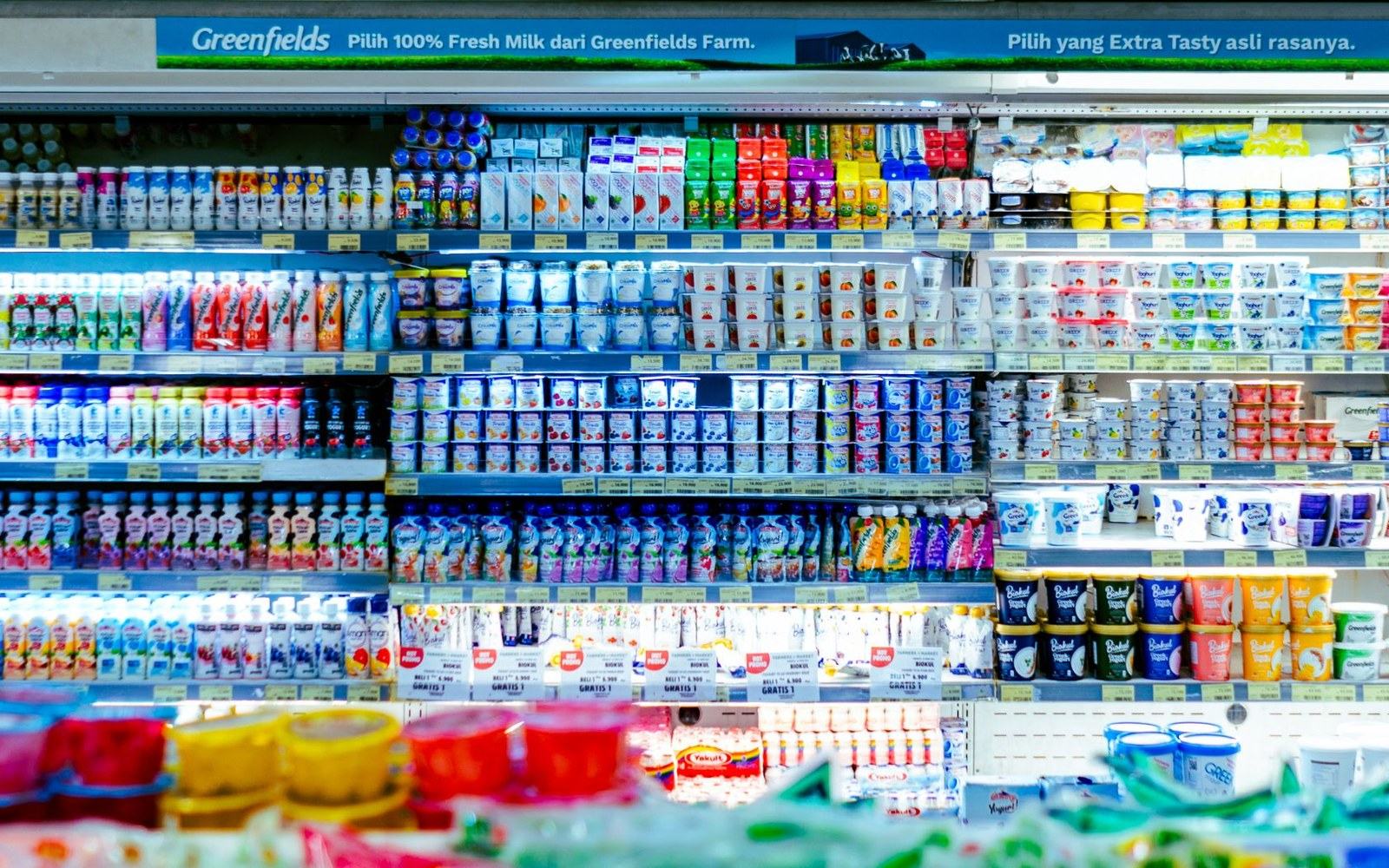 A refrigerated dairy aisle at the rear of a shop